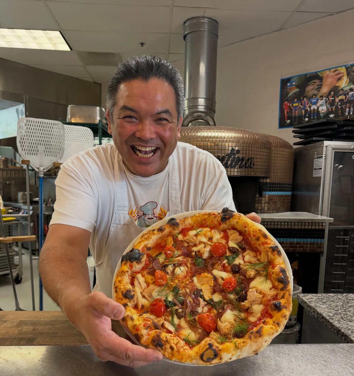 Chef Daisuke presenting a freshly baked pizza