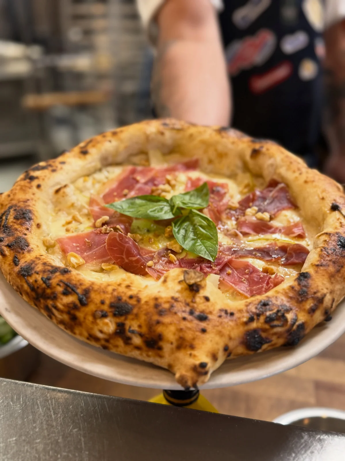 Pizza with prosciutto, basil and walnuts